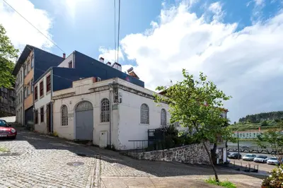 a white building with a blue roof on a street at Marias River Apartment in Porto