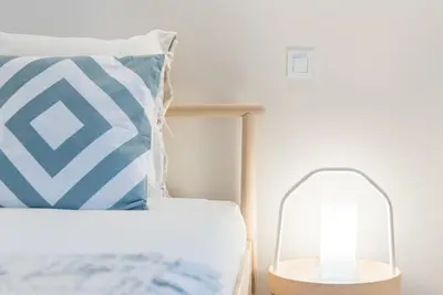 a bed with a blue and white pillow and a lamp at GuestReady - Bay Watch in Porto