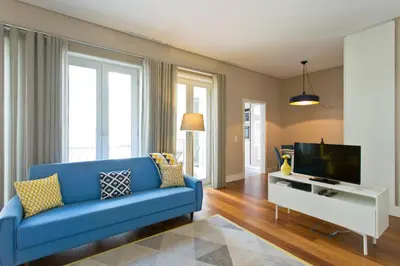 a living room with a blue couch and a tv at Cardosas Square Apartments by Porto City Hosts in Porto
