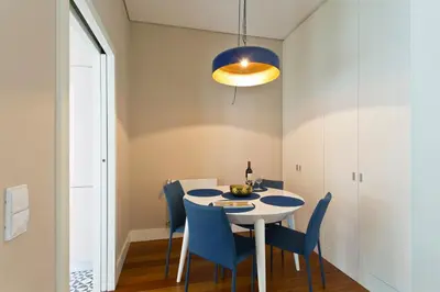 a dining room with a white table and blue chairs at Cardosas Square Apartments by Porto City Hosts in Porto