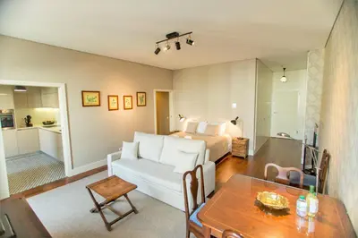 a living room with a white couch and a bed at Cardosas Square Apartments by Porto City Hosts in Porto