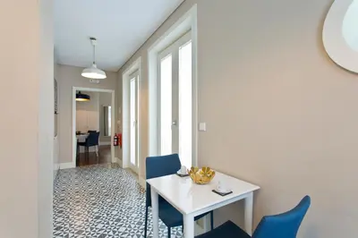 a bedroom with a white bed and a dining room at Cardosas Square Apartments by Porto City Hosts in Porto