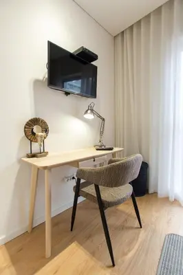a wooden desk with a chair and a television on a wall at Ninon- Premium Trindade by Porto City Hosts in Porto