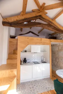 a kitchen with white cabinets and wooden ceilings at Picasso Suites Porto by PCH in Porto