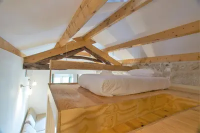 a bed on a wooden platform in a room with wooden beams at Picasso Suites Porto by PCH in Porto