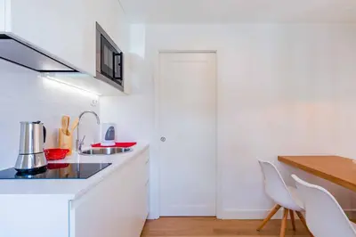 a white kitchen with white counters and white chairs at Lemago Porto Apartments - Sé in Porto