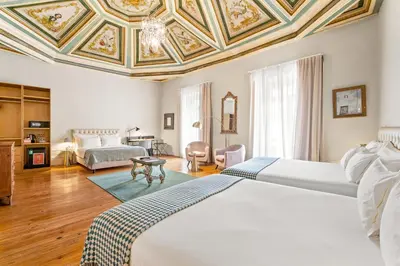 a bedroom with a white bed and a green chair at Casa dos Lóios by Shiadu in Porto
