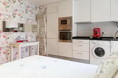 a kitchen with white cabinets and a washer and dryer at Casas do Teatro in Porto