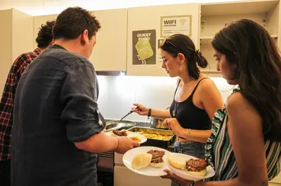 a group of people standing in a kitchen holding plates of food at Onefam Ribeira in Porto