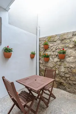 a wooden table and chairs next to a stone wall with potted plants at ZD Moreira Flats A By PortoProperties4You in Porto