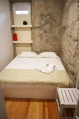 a bedroom with a white bed with a stone wall at ZD Moreira Flats E By PortoProperties4You in Porto
