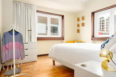 a bedroom with a large white bed and windows at Big Families & Groups Bonjardim views 5 bedrooms 3 bathrooms in Porto