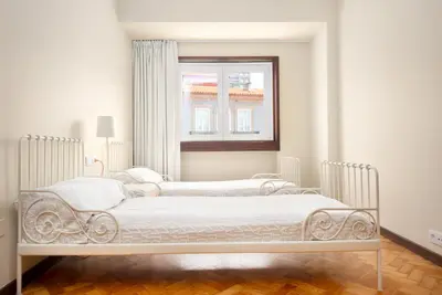two beds in a white room with a window at Big Families & Groups Bonjardim views 5 bedrooms 3 bathrooms in Porto