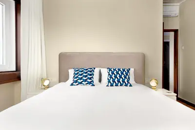 a bedroom with a white bed with blue and white pillows at Big Families & Groups Bonjardim views 5 bedrooms 3 bathrooms in Porto