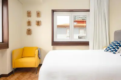 a bedroom with a bed and a yellow chair at Big Families & Groups Bonjardim views 5 bedrooms 3 bathrooms in Porto