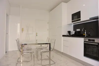 a white kitchen with a glass table and chairs at VB Porto City Apartment by Flat in Porto in Porto