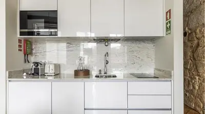 a kitchen with white cabinets and a stone wall at Wonderful Porto Design Apartments in Porto