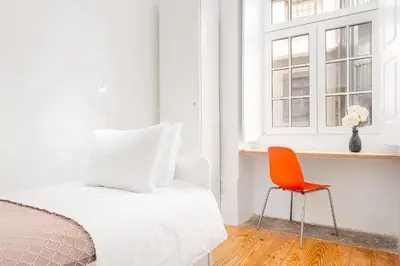 a bedroom with a bed and a orange chair at Host Wise - Oporto Classic Apartment in Porto