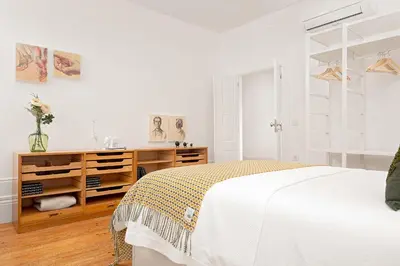 a white bedroom with a bed and a wooden dresser at Host Wise - Oporto Classic Apartment in Porto