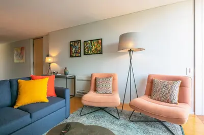 a living room with two chairs and a lamp at Porto Insight Cedofeita- Parking, Balconies & AC in Porto