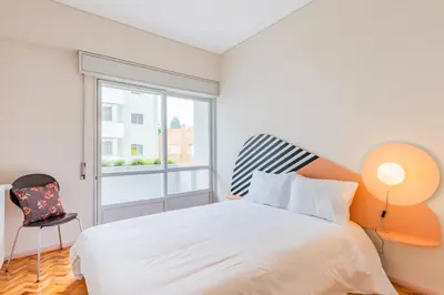 a white bedroom with a bed and a window at AMAZING DUPLEX - Mid Century Experience & PARKING in Porto