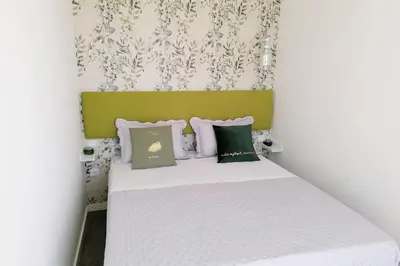 a small bedroom with a white bed with green headboard at Window Garden Apartment in Porto
