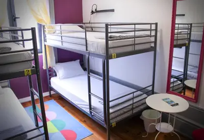 a room with two bunk beds and a table at By Doors Hostel in Porto