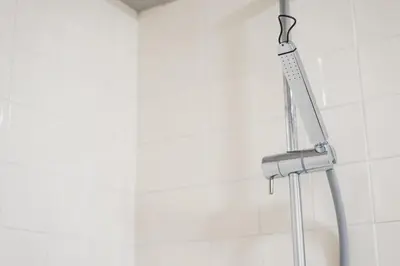 a shower head in a white tile bathroom at Cedofeita Lux Design in Porto