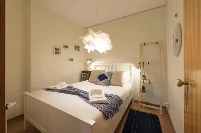 a bedroom with a large white bed with a chandelier at LovelyStay - The Porto Getaway w/ Free Parking in Porto