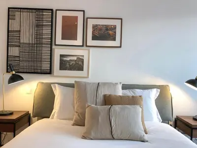a bedroom with a white bed with four pictures on the wall at Oporto Chic&Cozy - Aliados in Porto