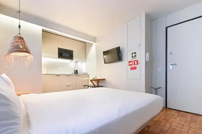 a bedroom with a large white bed and a kitchen at Sleep in Office in Porto