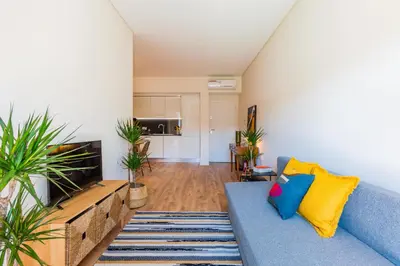a living room with a blue couch and a tv at Boavista Garden Apartment in Porto