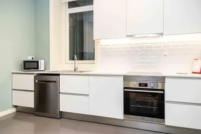 a kitchen with white cabinets and a sink and a microwave at VIVA Size Flats Clérigos in Porto