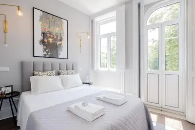 a white bedroom with a bed with two towels on it at Plaza-Charming GuestHouse in Porto