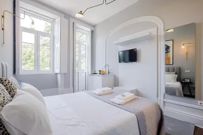 a white bedroom with a bed and a mirror at Plaza-Charming GuestHouse in Porto