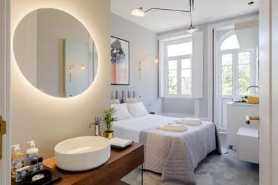 a bathroom with a bed and a sink and a mirror at Plaza-Charming GuestHouse in Porto