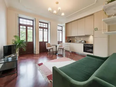 a living room with a green couch and a kitchen at Trindade Premium Apartments in Porto