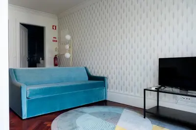 a living room with a blue couch and a tv at Trindade Premium Apartments in Porto