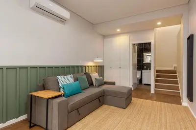a living room with a gray couch and a staircase at Feel Porto Wine Essence Apartments in Vila Nova de Gaia