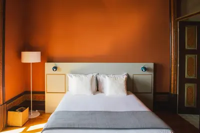 a bedroom with a bed with an orange wall at Menina Colina Guesthouse in Porto