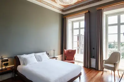 a bedroom with a white bed and two windows at Menina Colina Guesthouse in Porto