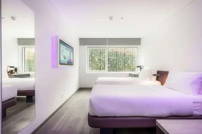 a white room with two beds and a television at YOTEL Porto in Porto