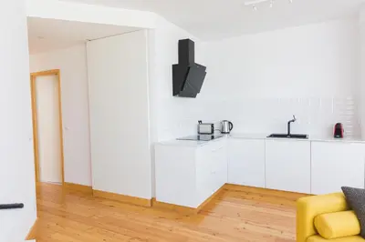 a kitchen with white cabinets and a yellow chair at Aposentus - Skyline Porto in Porto