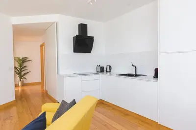 a white kitchen with a yellow couch in a living room at Aposentus - Skyline Porto in Porto