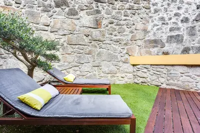 a patio with two benches and a stone wall at Pinheiro Terrace Downtown Apartment by DA'HOME in Porto