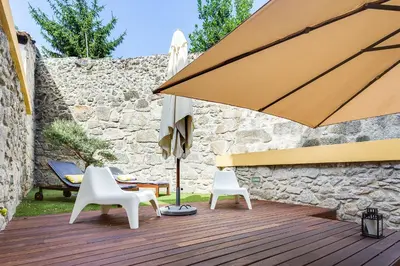 a wooden deck with two chairs and an umbrella at Pinheiro Terrace Downtown Apartment by DA'HOME in Porto