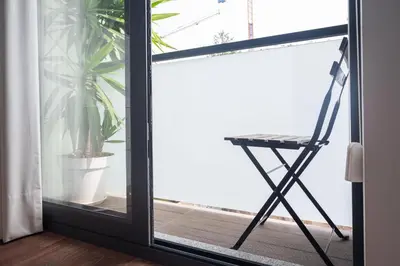 a chair sitting on a balcony next to a window at Sunflower Luxury Loft w AC Downtown and Metro in Porto