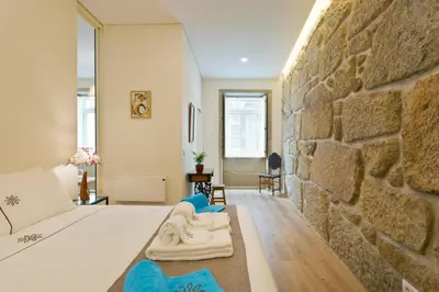 a bedroom with a stone wall and a bed at Estrela de Gaia Apartments in Vila Nova de Gaia