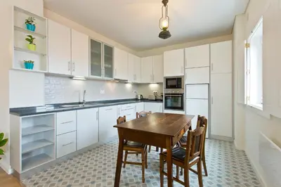 a kitchen with white cabinets and a wooden table and chairs at Estrela de Gaia Apartments in Vila Nova de Gaia