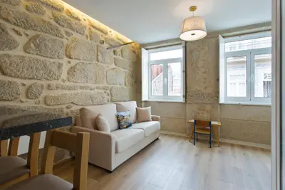 a living room with a couch and a stone wall at Estrela de Gaia Apartments in Vila Nova de Gaia